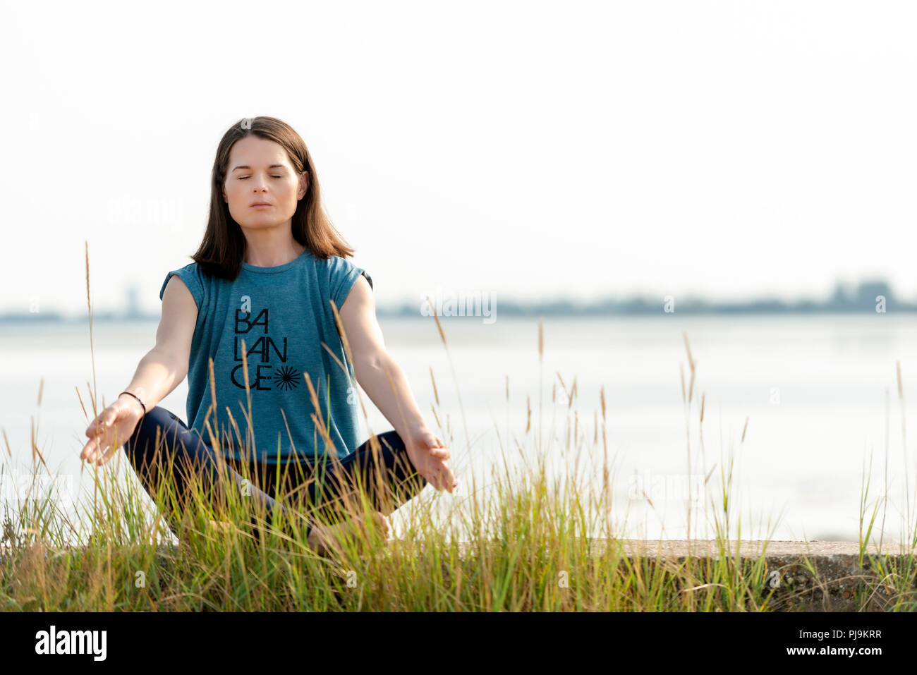 Donna seduta gambe incrociate e la meditazione Foto Stock