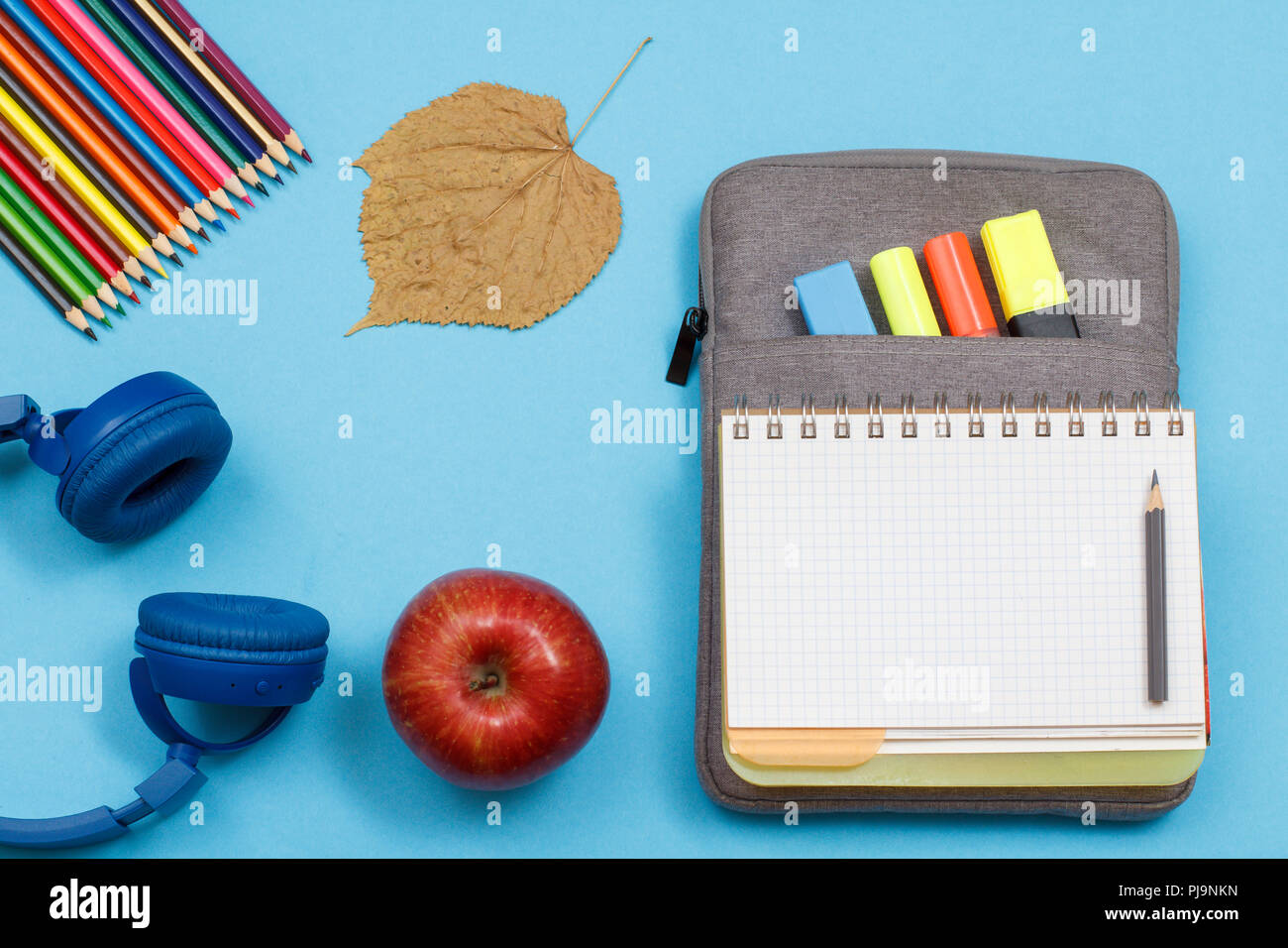 Cuffie, matite colorate, Apple, foglia secca, aprire il quaderno sul  sacchetto custodia a matita con colore pennarelli e un marcatore su sfondo  blu. Vista dall'alto. Torna t Foto stock - Alamy
