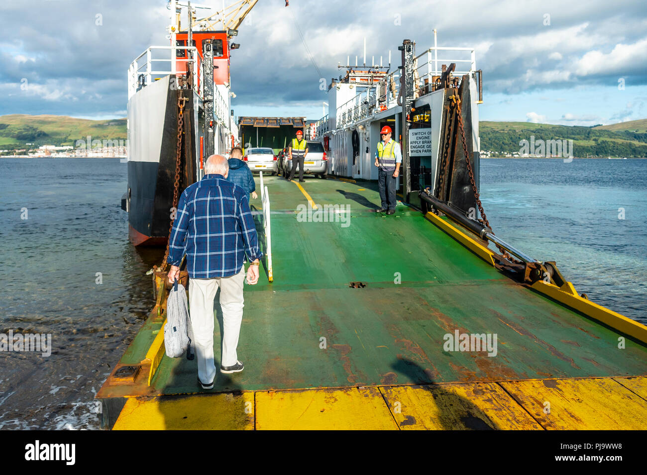 I passeggeri di salire a bordo del traghetto ro-ro Loch Riddon dall'Isola di Cumbrae, con la città balneare destinazione di Largs in background. Foto Stock