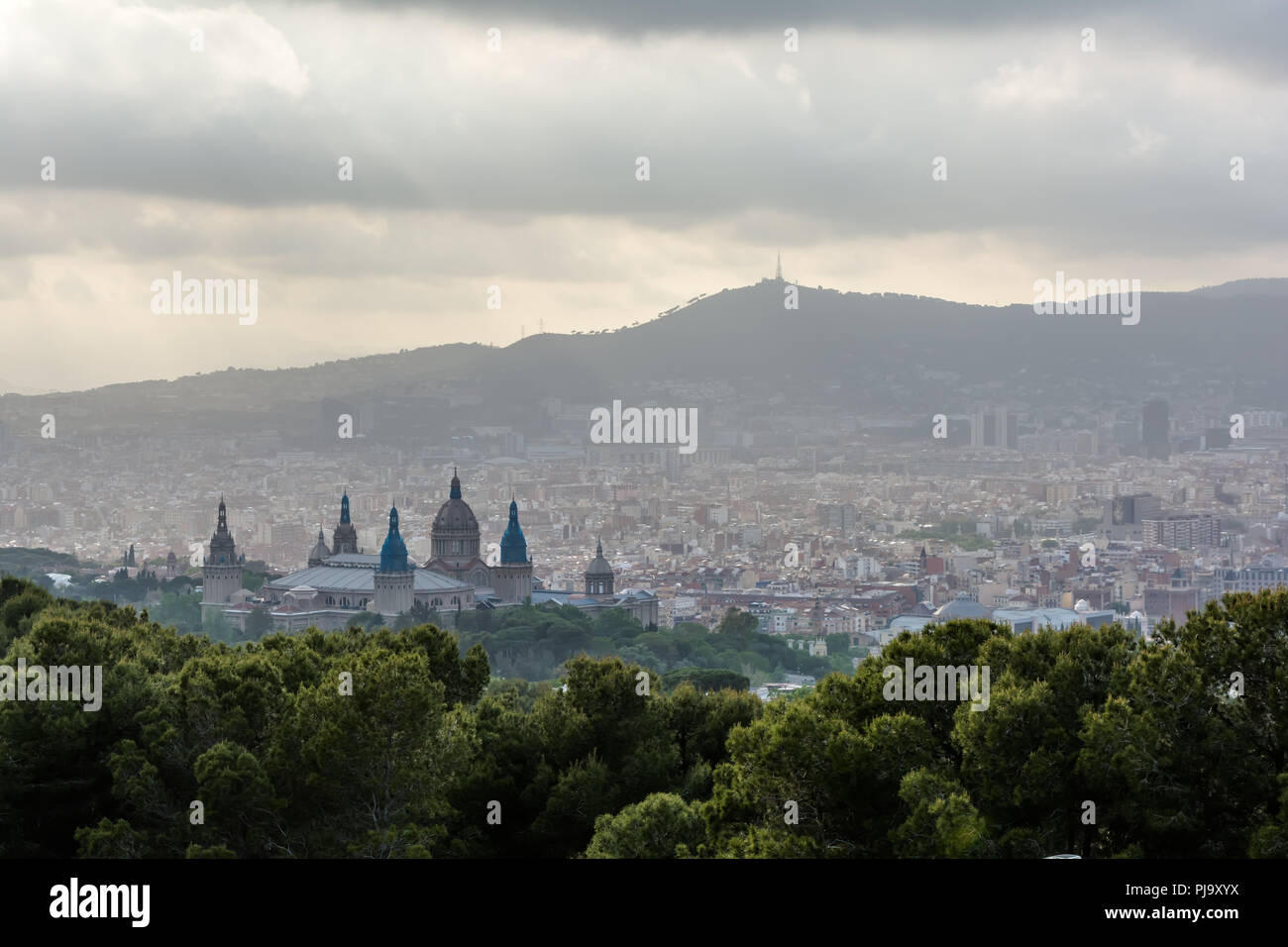 Vista a Barcellona città dalla collina di Montjuic nuvoloso in serata con il Palau Nacional (Palazzo Nazionale) cupole rinascimentali in primo piano. Foto Stock