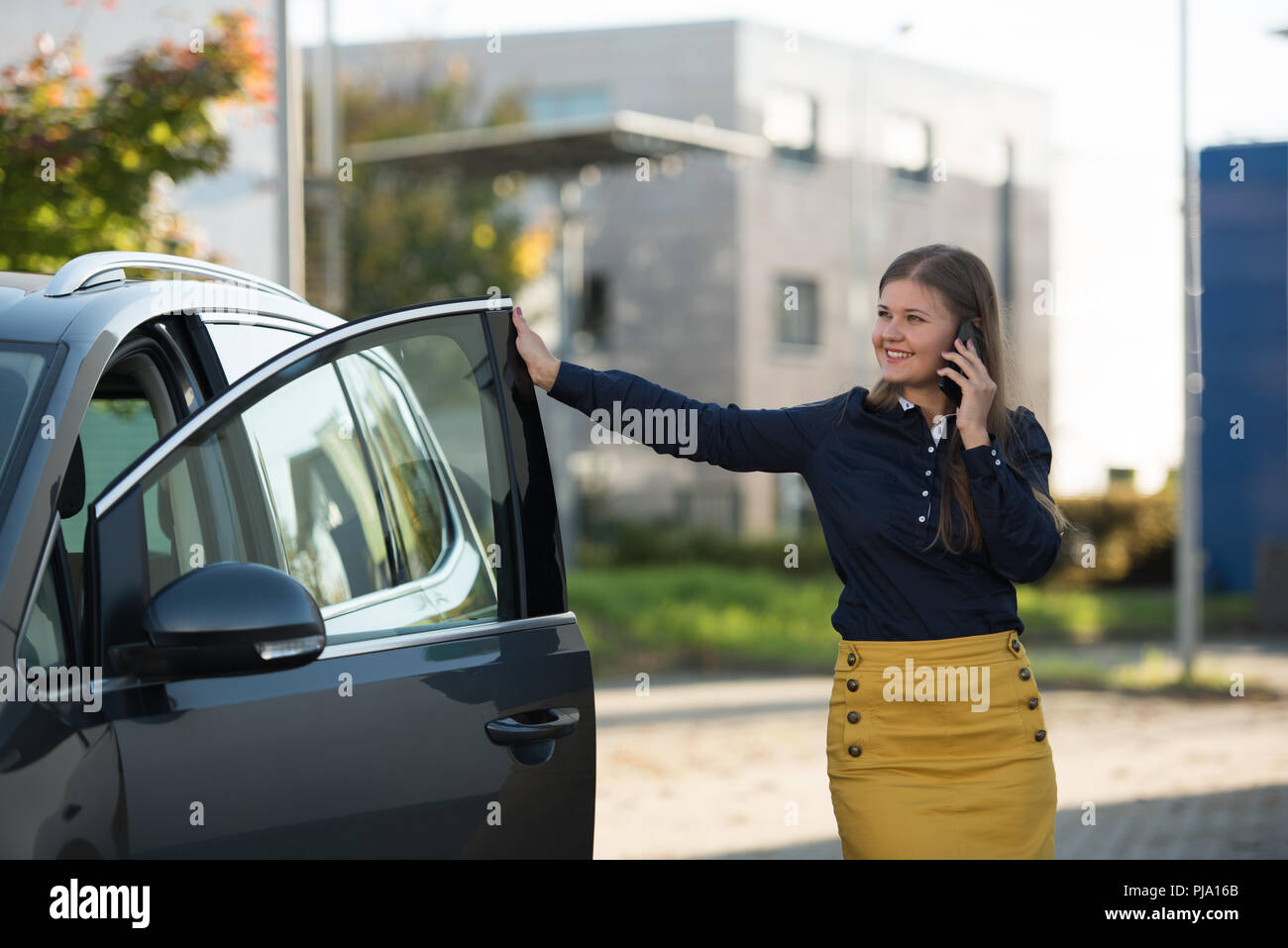 Giovane donna con lo smartphone si apre la porta e arriva in auto Foto Stock Giovane donna con lo smartphone si apre la porta e arriva in auto Foto Stock