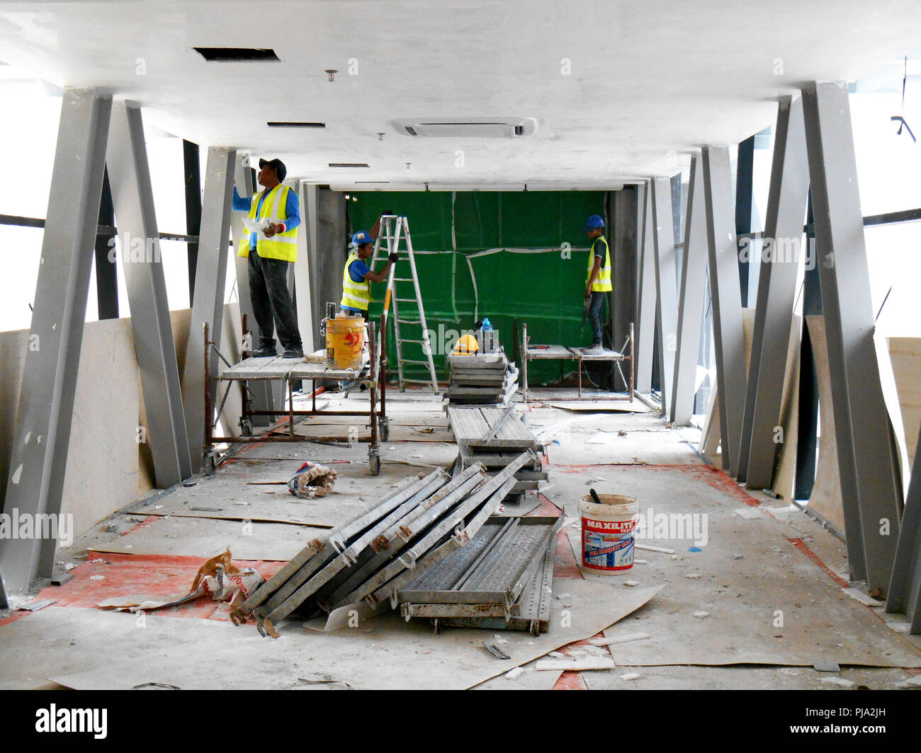 Sito in costruzione i lavoratori stanno facendo intradosso soffitto foglietta lavoro presso il sito di costruzione. Base e finale dello strato di rivestimento di applicare per ottenere la superficie liscia. Foto Stock