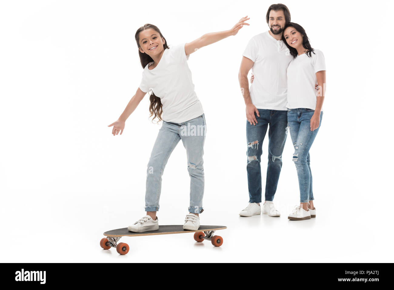 Sorridente genitori guardando la figlia il pattinaggio su skateboard isolato su bianco Foto Stock