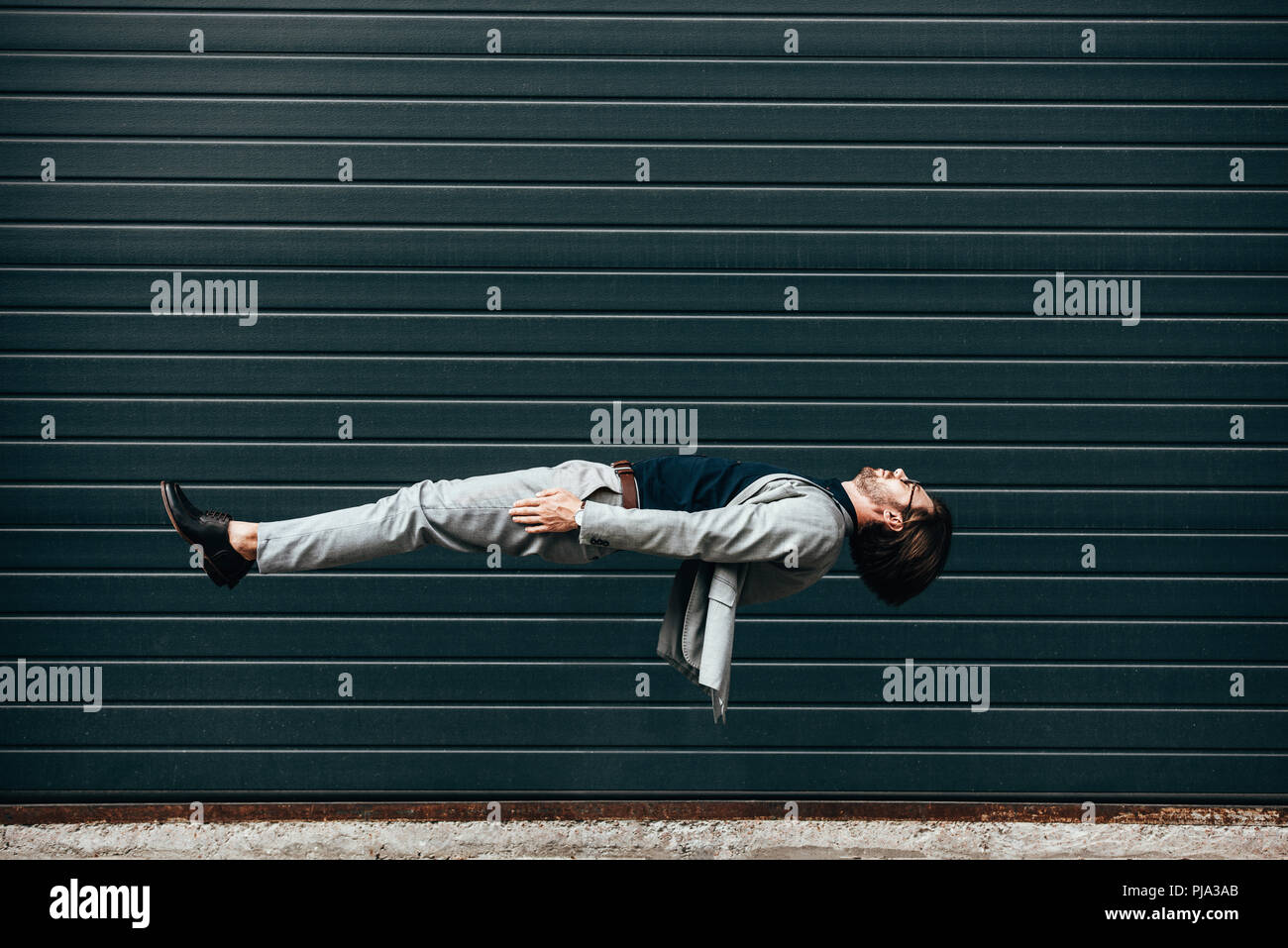 Vista laterale del giovane imprenditore sdraiato sulla schiena in aria nella parte anteriore del porta rullo Foto Stock