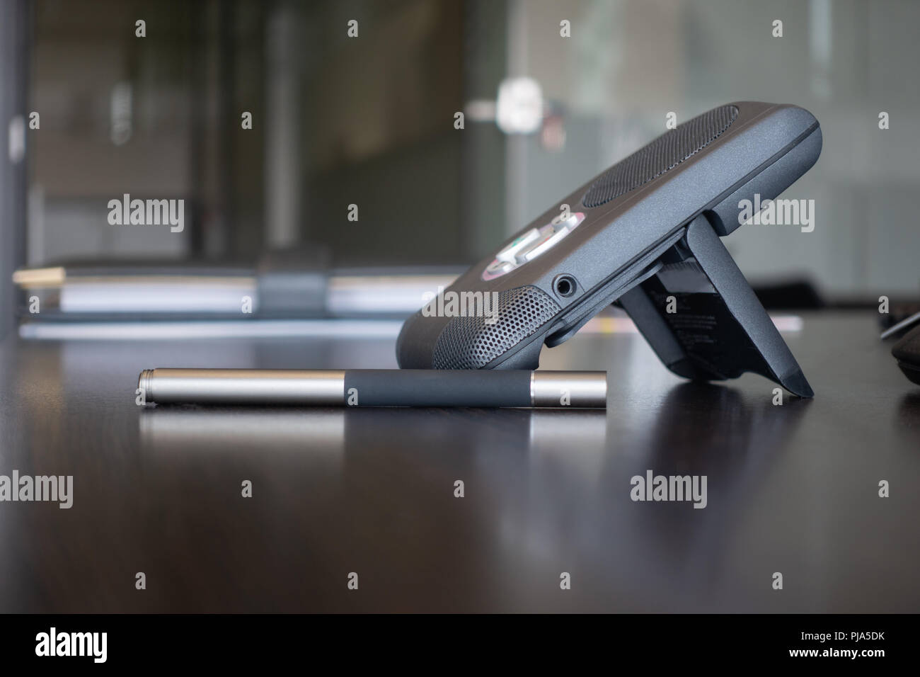 Il dispositivo di comunicazione wireless voice over internet phone su pulire, marrone scuro scrivania da ufficio, penna stilo sul tavolo e classic cartella business portfolio ho Foto Stock