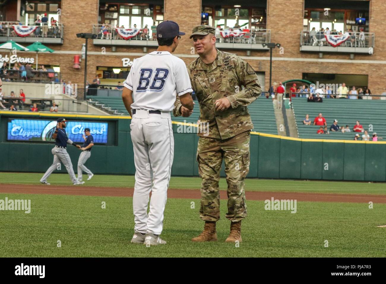 Ohio Army National Guard Sgt. 1. Classe Michael Mullen riceve un baseball commemorative da Columbus Clippers palla ragazzo dopo Mullen ha gettato fuori il cerimoniale di primo passo prima la Clippers' gioco vs la Toledo Mud Hens Luglio 5, 2018 a Huntington Park in Columbus, Ohio. Mullen ha ricevuto l'onore di buttare il primo passo per la sua esemplare esperienza militare che include un cuore viola ha guadagnato mentre serve oltreoceano a sostegno della guerra al terrorismo. (Ohio National Guard Foto Stock