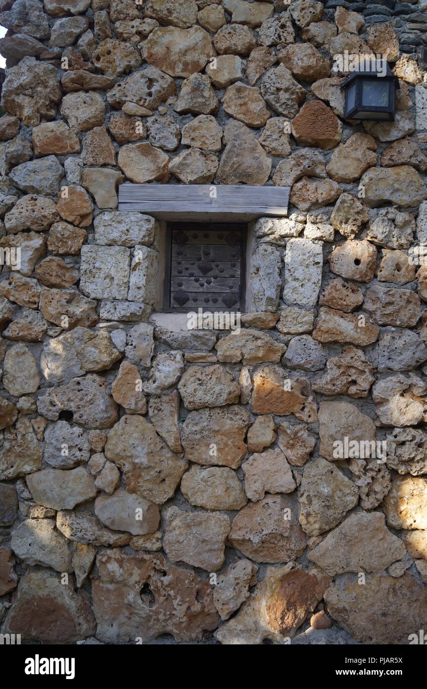Ferro da stiro tradizionali e finestra di legno su un muro di pietra da un vecchio edificio in una cittadina turistica della Repubblica Dominicana Foto Stock