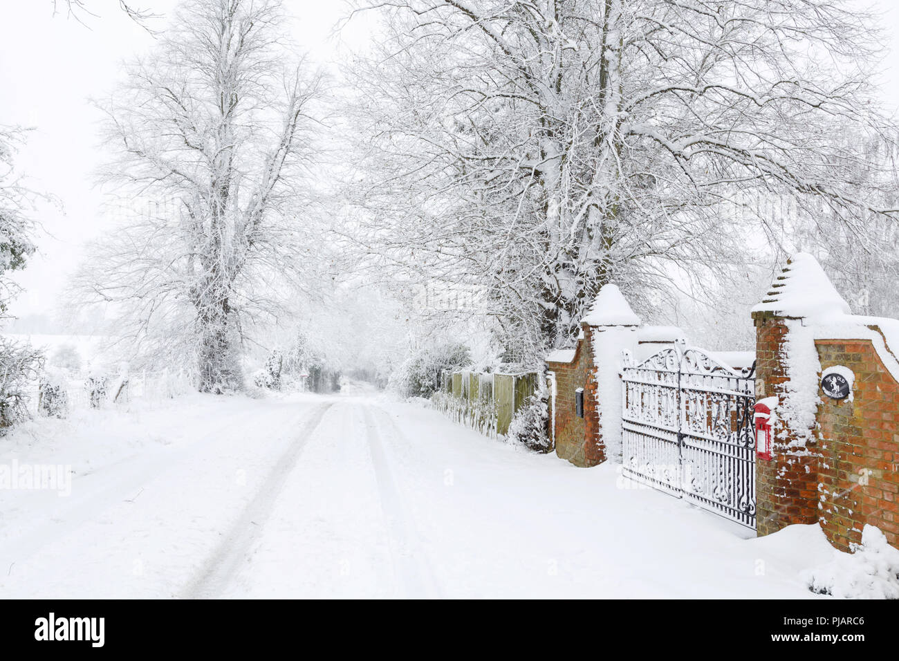 Coperte di neve strada britannica fuori dall'ingresso di una vecchia casa circondata dalla campagna in inverno Foto Stock