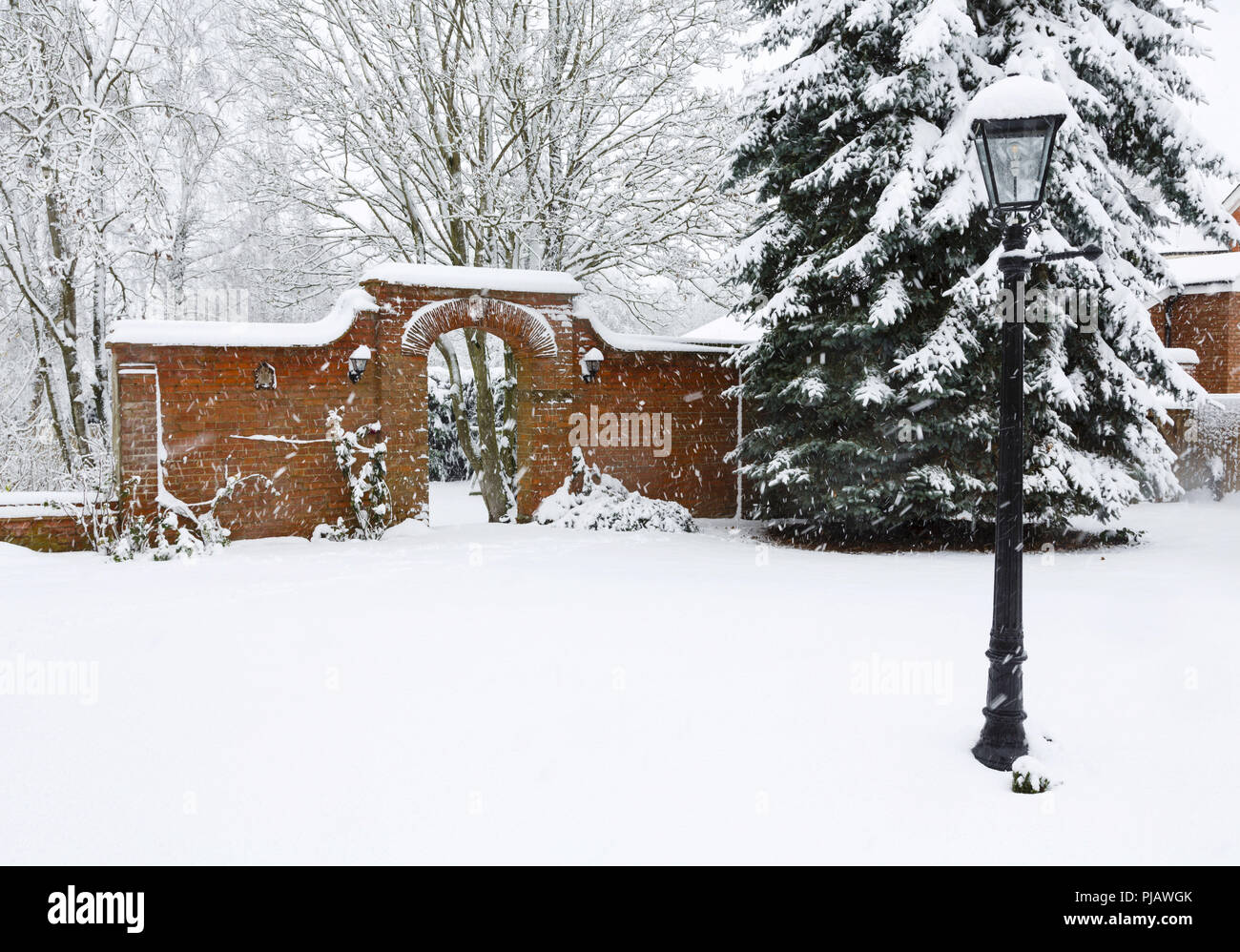 Un Victorian walled garden e arco in mattoni coperte di neve in inverno Foto Stock