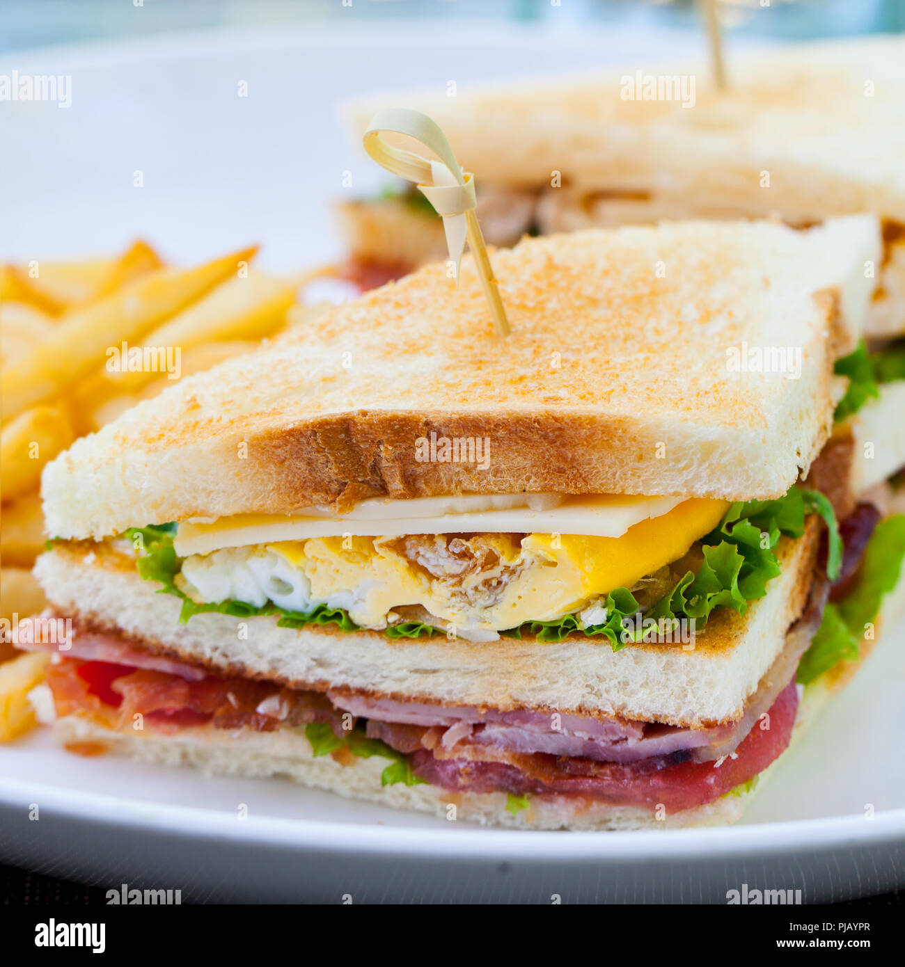 Club sandwich con patatine fritte su una piastra bianca. Estate sfondo all'aperto. Close up. Foto Stock