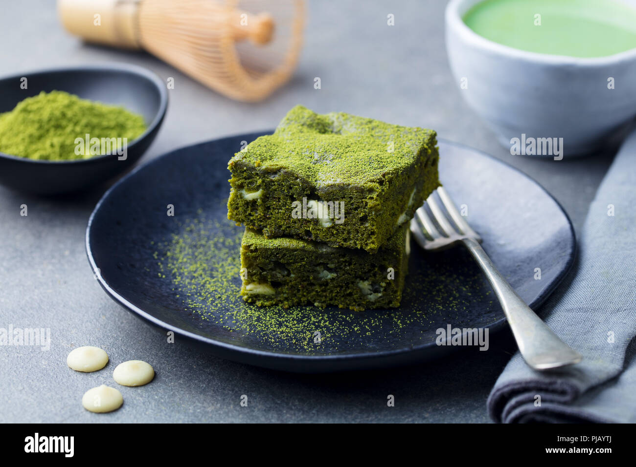 Tè verde Matcha torta, barre, brownie con il cioccolato bianco su una piastra. Sfondo grigio. Foto Stock