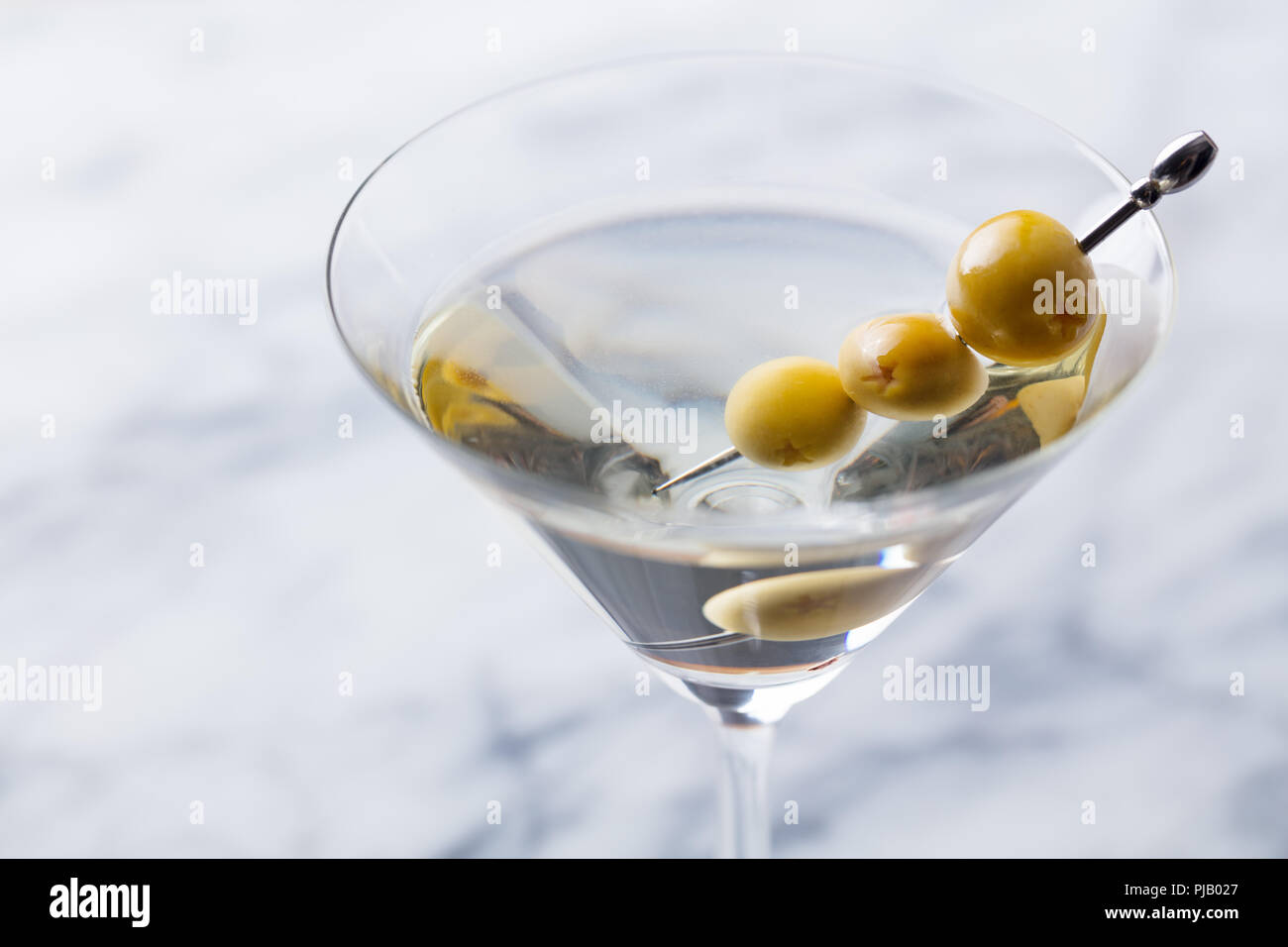 Martini cocktail con olive verdi sul bordo di marmo. Close up. Foto Stock