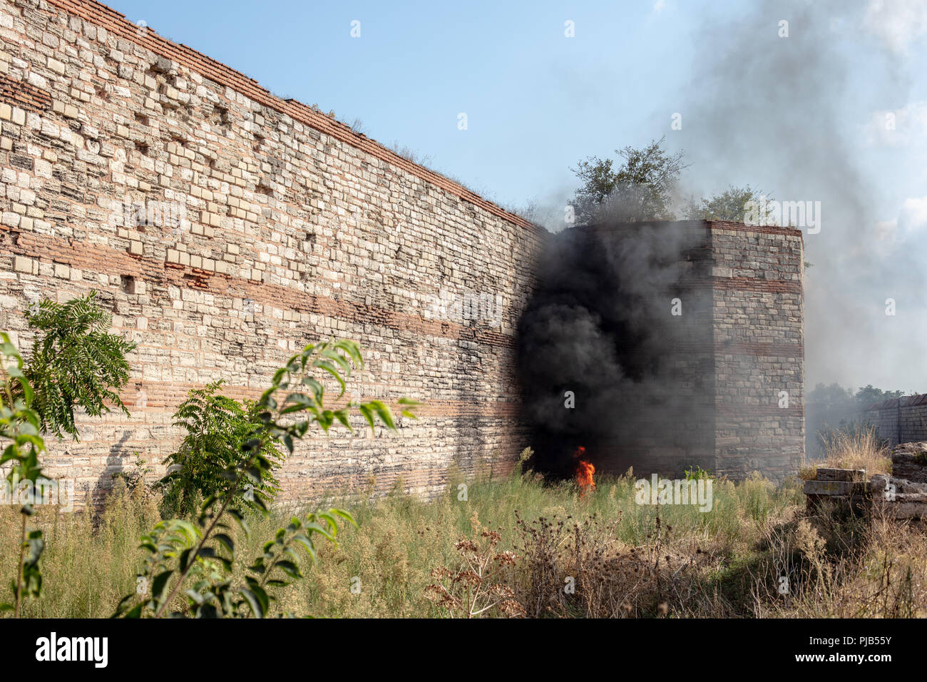Un fuoco e il fumo nei pressi delle rovine delle mura di Costantinopoli. (Oggi Istanbul in Turchia) Foto Stock