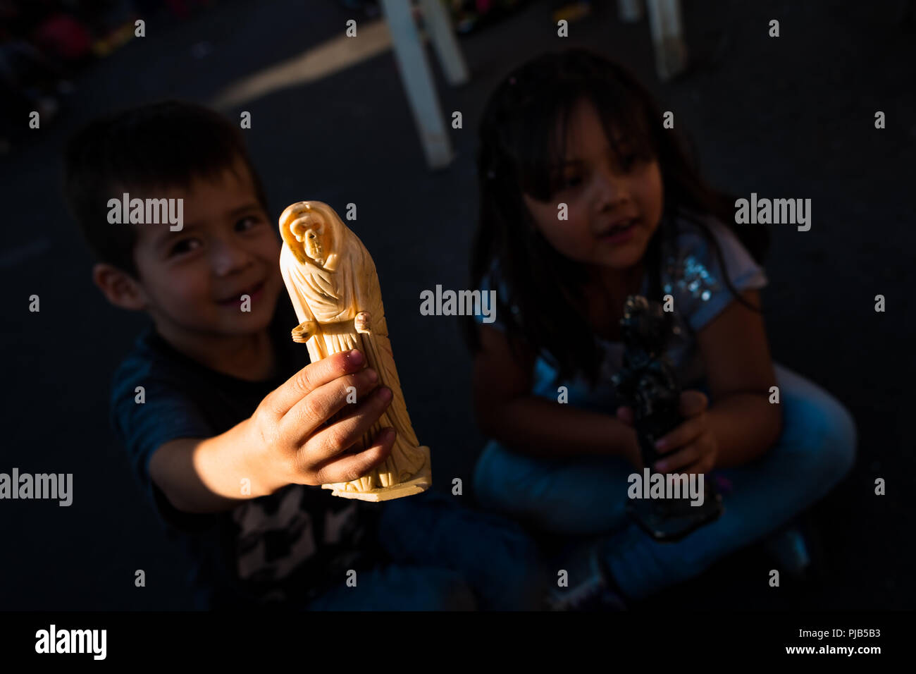 Un ragazzo messicano, seduta accanto a sua sorella, mostra una figurina di Santa Muerte (Santa morte) durante un religioso pellegrinaggio a Città del Messico. Foto Stock