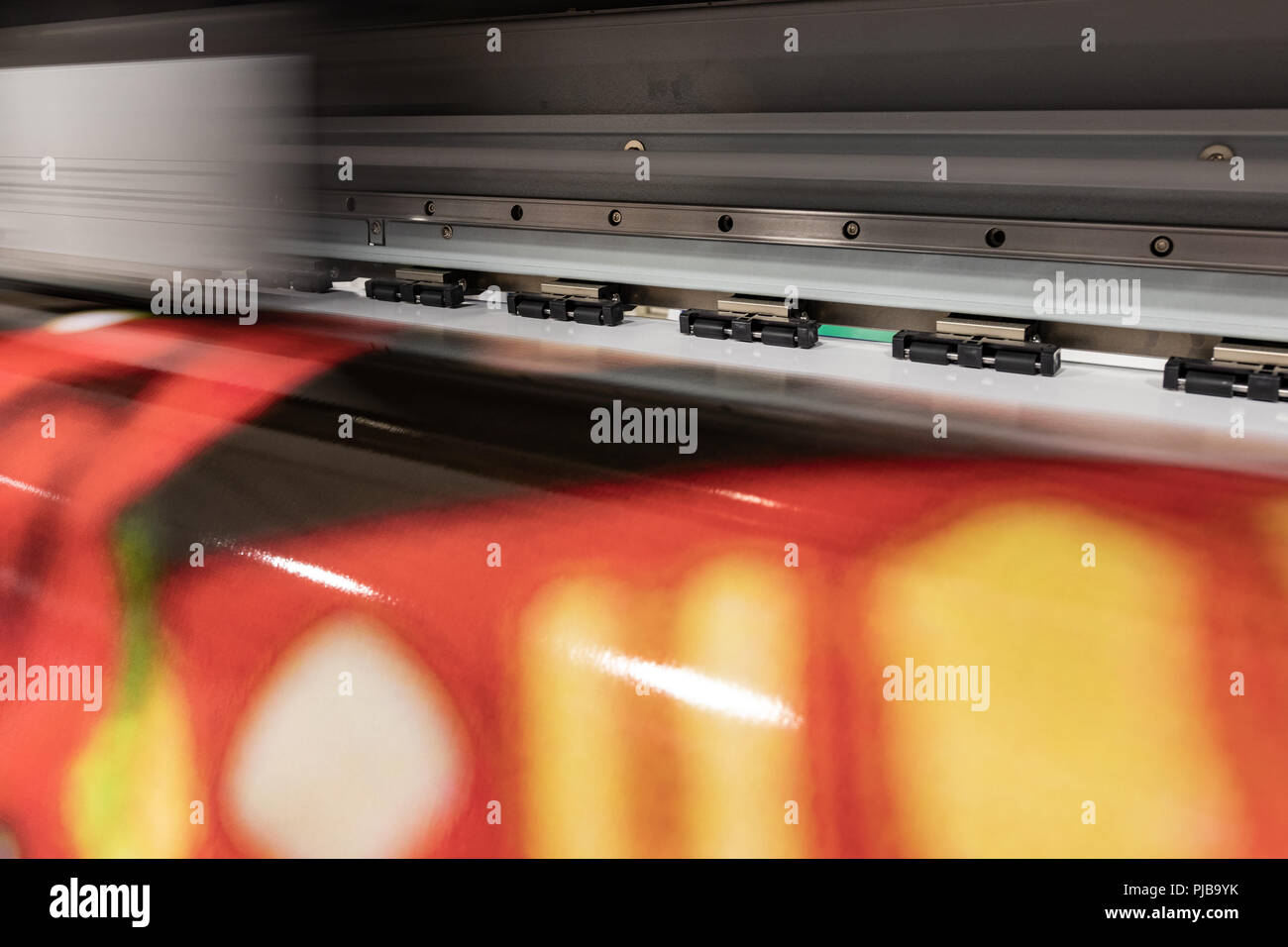 Grande stampante professionale, elaborazione grandi rotoli di vinile per campionamento del colore in un enorme ambiente di produzione. Foto Stock