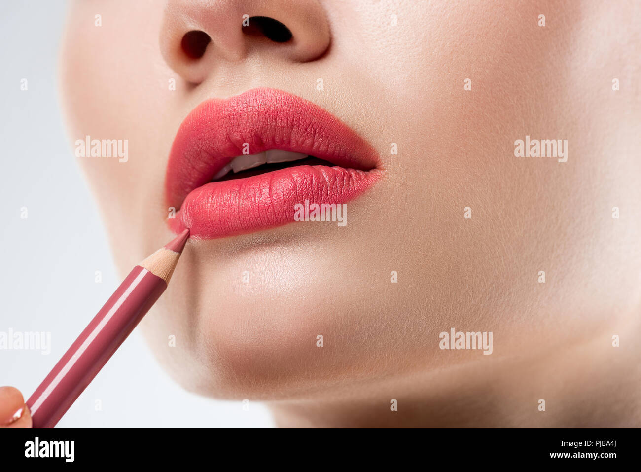 Close up studio shot della donna applicando labbro matita, isolato su bianco Foto Stock