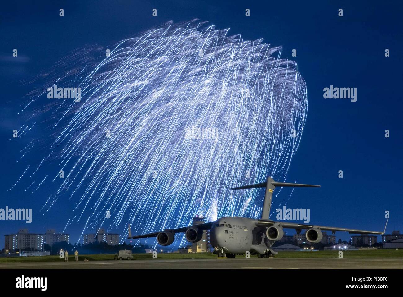 Fuochi d'artificio esplodere dietro un U.S. Air Force C-17 Globemaster III aeromobile assegnati al XV ala durante il processo di celebrare l'America, 3 luglio, 2018 a Yokota Air Base, Giappone. Celebrare l America è un evento annuale che prevede organi militari e alle loro famiglie la possibilità di godere appieno dei giochi, cibo e bande prima di culminare in uno spettacolo di fuochi d'artificio su Yokota AB airfield per celebrare il Giorno di Indipendenza. Foto Stock