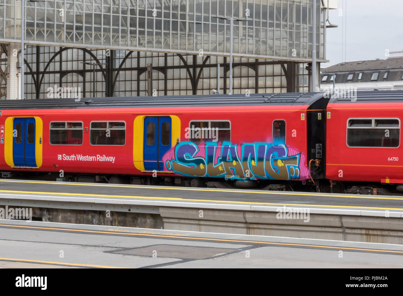 A sudovest di convoglio ferroviario nella piattaforma alla stazione Waterloo di Londra con graffiti sul lato Foto Stock