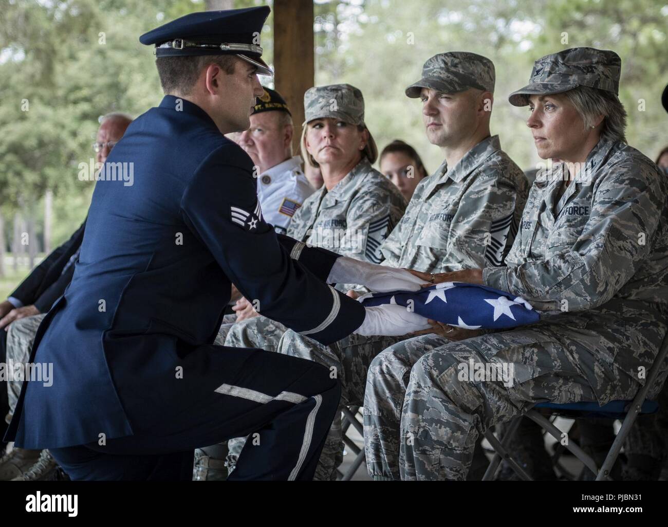 Senior Airman Zachary Brady, 96Medical Group, presenta un flag per Col. Denise Edwards, 96Test ala, durante la Guardia d'onore cerimonia di laurea 9 Luglio al Eglin Air Force Base, Fla. circa 14 nuovi aviatori graduata da 120-plus-ore di corso. La graduazione prestazioni include bandiera dettaglio, fucile volley, Pall portatori e bugler per amici e familiari e comandanti dell'unità. Foto Stock