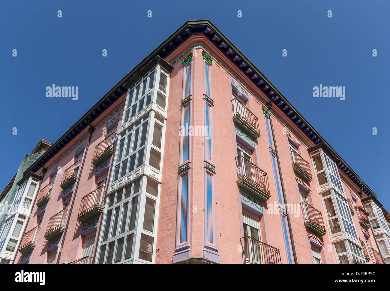 Una facciata storica di un rosa edificio ad angolo a Burgos, Spagna Foto Stock