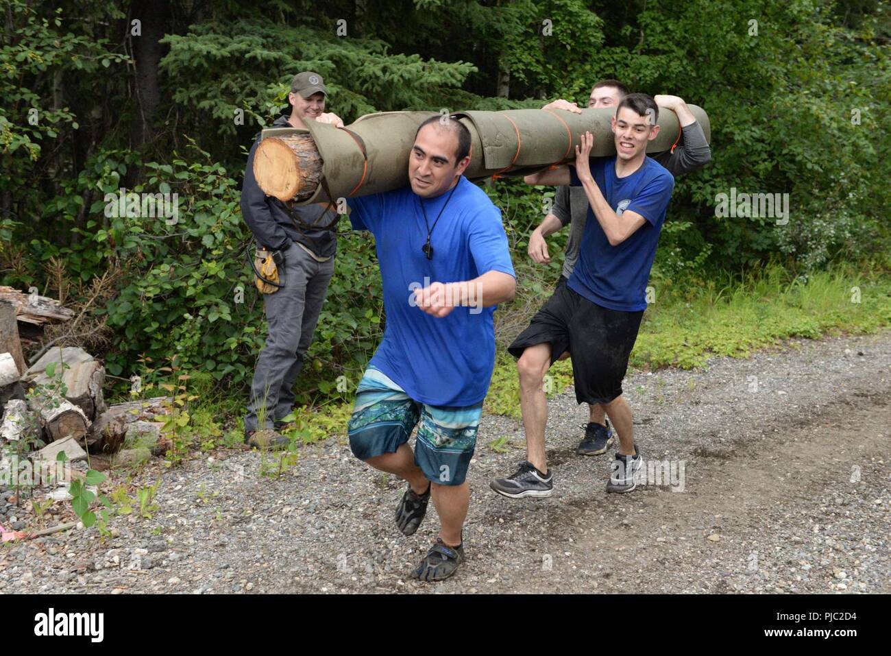 Stati Uniti Air Force Technical Sgt. Daniel Rodriguez, la 353 CTS NCOIC gli obiettivi e i suoi compagni di squadra portano un log attraverso la linea del traguardo alla sopravvivenza artica 5k fango Run, luglio 16, 2018 a Eielson Air Force Base in Alaska. Il fango eseguire aveva quattro ostacoli per le squadre di viaggiare attraverso durante la gara. Foto Stock