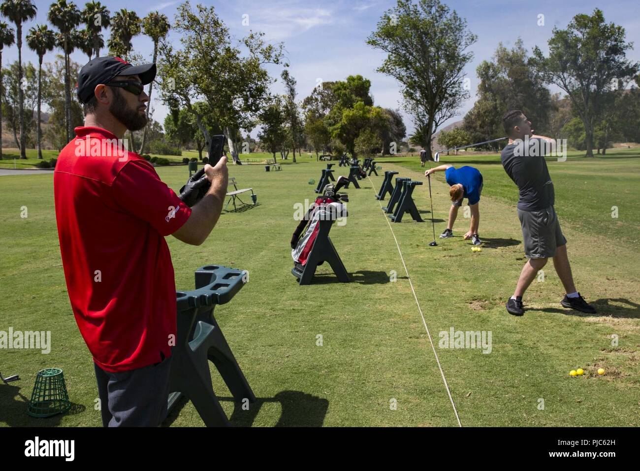 Phil Bryant, tiro e golf coach, guerriero ferito Battalion-West, registra la forma di lancia cpl. Dylan Stovall e Giacobbe Grawe al Marine Memorial Golf su Marine Corps base Camp Pendleton, California, 16 luglio 2018. Bryant registra ogni Marines' prestazioni per osservare miglioramenti apportati e per rimediare alle carenze riscontrate. Foto Stock