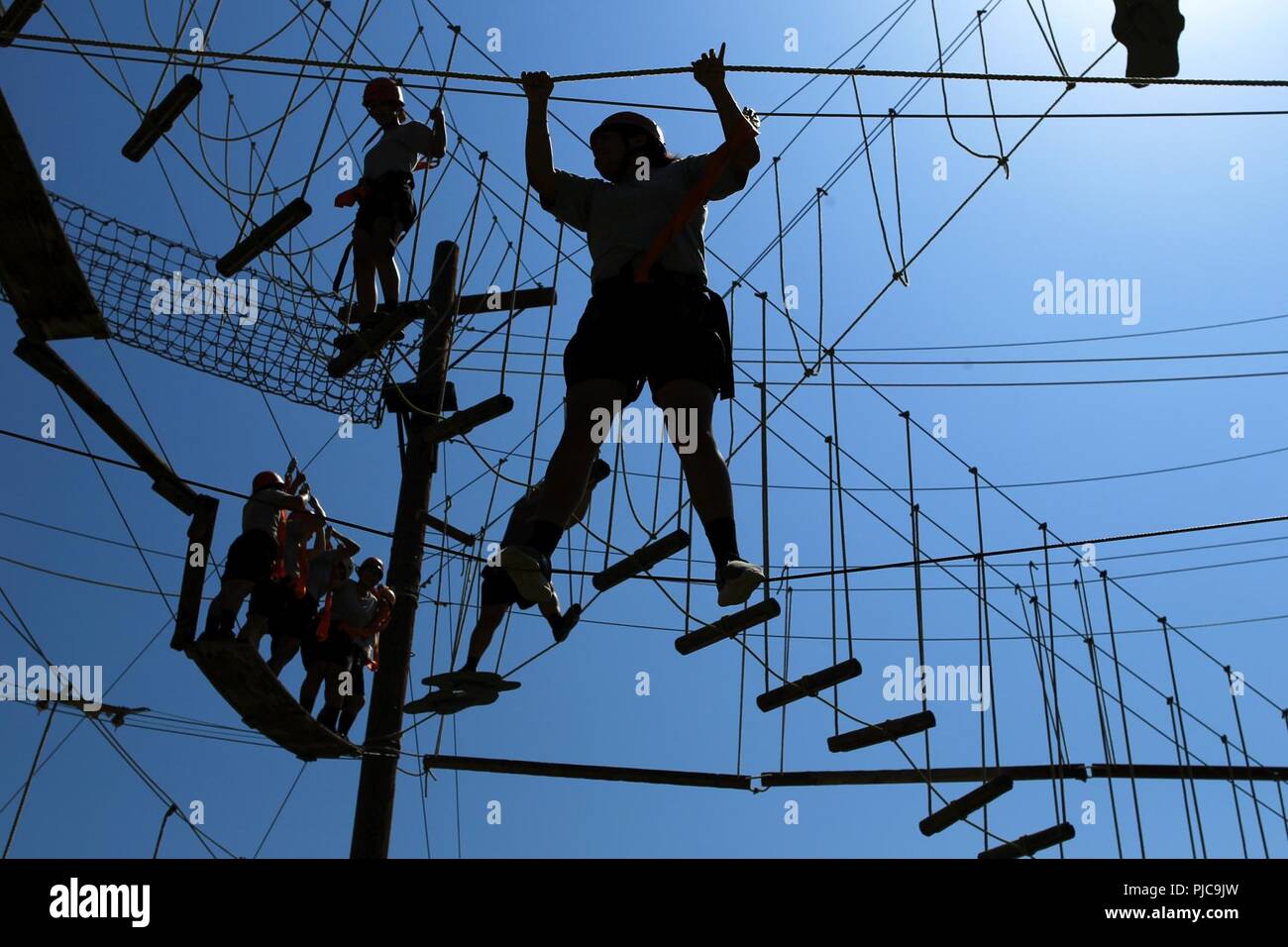 I candidati in Sunburst sfida della gioventù dell Accademia Classe 22 Firehawks plotone lavorare il loro modo attraverso un intricato sistema di corda ostacoli mentre l'ascendente di una zip line finish, luglio 19, 2018 all'Orange County ropes course di Anaheim, in California. Le funi corso offre ai candidati la possibilità di spingere se stessi sia mentalmente e fisicamente, per costruire la fiducia e di iniziare a lavorare come un team mentre è ancora in fase di acclimatazione della sfida del programma. Foto Stock