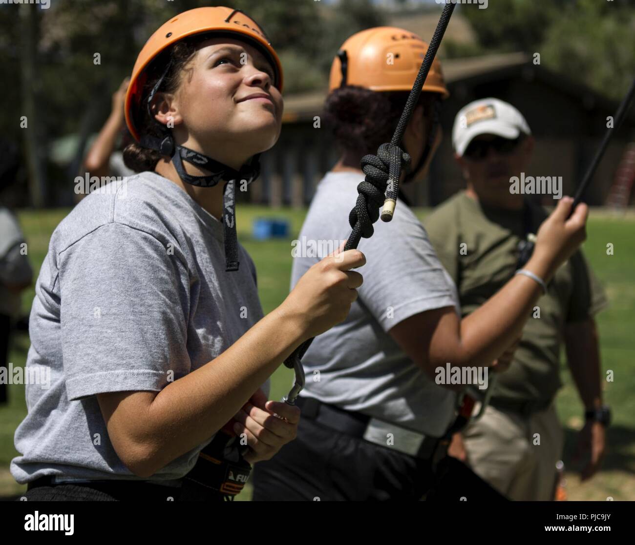 Lucia Harrington, un candidato in Sunburst sfida della gioventù dell Accademia Classe 22 Firehawks plotone, guarda fino alla scaletta di corda e la parete di arrampicata che inizia la sua ascesa di una fune tower, luglio 19, 2018 all'Orange County ropes course di Anaheim, in California. Le funi corso offre ai candidati la possibilità di spingere se stessi sia mentalmente e fisicamente, per costruire la fiducia e di iniziare a lavorare come un team mentre è ancora in fase di acclimatazione della sfida del programma. Foto Stock
