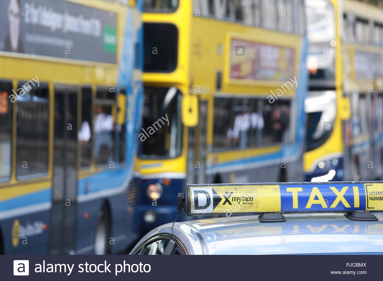 Un segno di taxi sul tetto di un taxi di Dublino con autobus di Dublino in background Foto Stock
