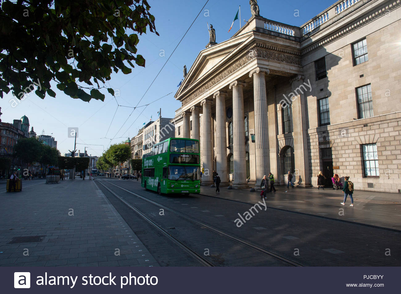Un verde Dublin Bus viaggi ultimi GPO in O'Connell Street come il sole illumina uno dell'Irlanda più famosi palazzi, scena della ribellione 1916 Foto Stock