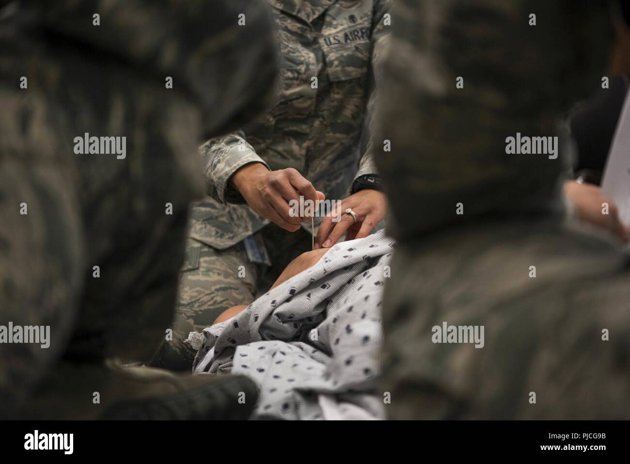 Stati Uniti Air Force Master Sgt. Demetris Johnson, un multi-unità di servizio di volo capo assegnato al 673d Inpatient Operations Squadron, incarica 673d gruppo medico personale per eseguire una decompressione ad ago per una tensione pneumotorace durante un combattimento tattico Casualty Care corsi a base comune Elmendorf-Richardson, Alaska, 12 luglio, 2018. Questa procedura è necessaria quando aria entra nella cavità toracica impedendo il polmone di espansione. L'ago rilascia aria, lasciando il polmone espandono e il paziente respira ancora. Foto Stock