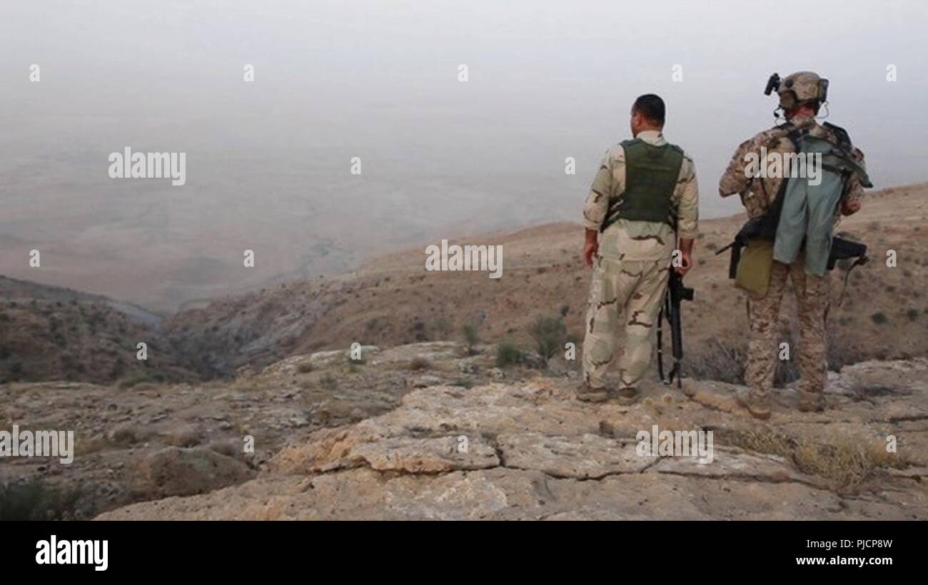 Un Peshmerga e le forze della coalizione hanno stati valutare il terreno durante una comune operazione di liquidazione in Makhmour, Iraq, 16 luglio 2018. Lo scopo della missione era quello di eliminare la presenza di ISIS in zona. La Coalizione continua a lavorare con i nostri partner per garantire sicurezza e protezione per il popolo iracheno. Foto Stock