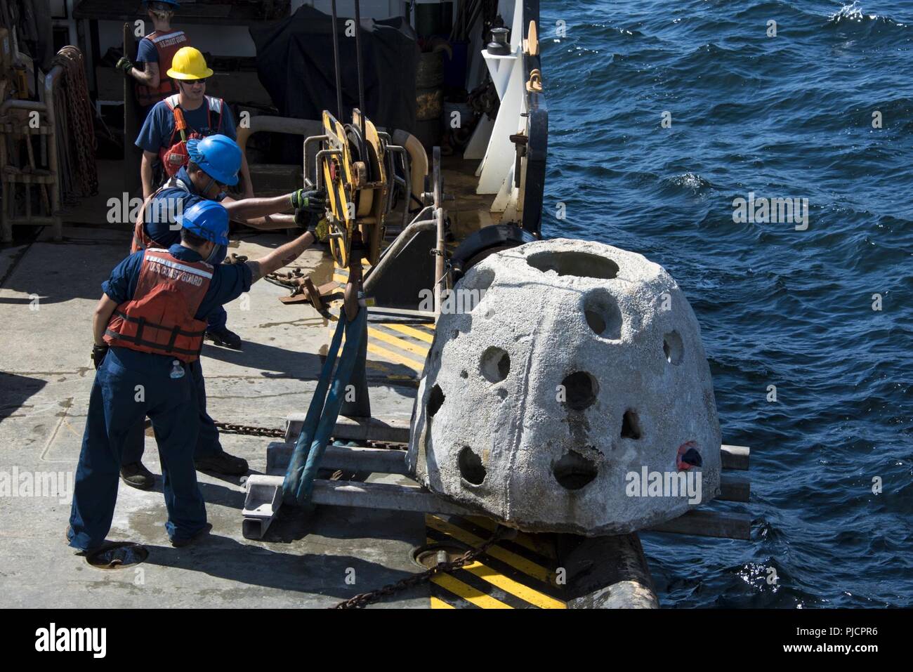 Guardacoste Maria Bray membri di equipaggio preparare per distribuire un calcestruzzo reef ball, luglio 18, 2018, al largo della costa della Florida nord-est. La Maria Bray equipaggio assistita nella distribuzione di reef palle, costruito da Mandarin gli studenti delle scuole superiori e vecchie ancore di navigazione per pensare che, lavello, Reef, o TISIRI al fine di creare una scogliera sottomarina habitat. Foto Stock