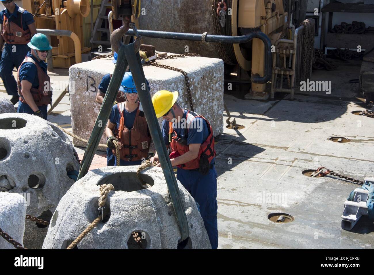 Guardacoste Maria Bray membri di equipaggio preparare un calcestruzzo reef ball per distribuzione, luglio 18, 2018, al largo della costa della Florida nord-est. La Maria Bray equipaggio assistita nella distribuzione di reef palle, costruito da Mandarin gli studenti delle scuole superiori e vecchie ancore di navigazione per pensare che, lavello, Reef, o TISIRI al fine di creare una scogliera sottomarina habitat. Foto Stock