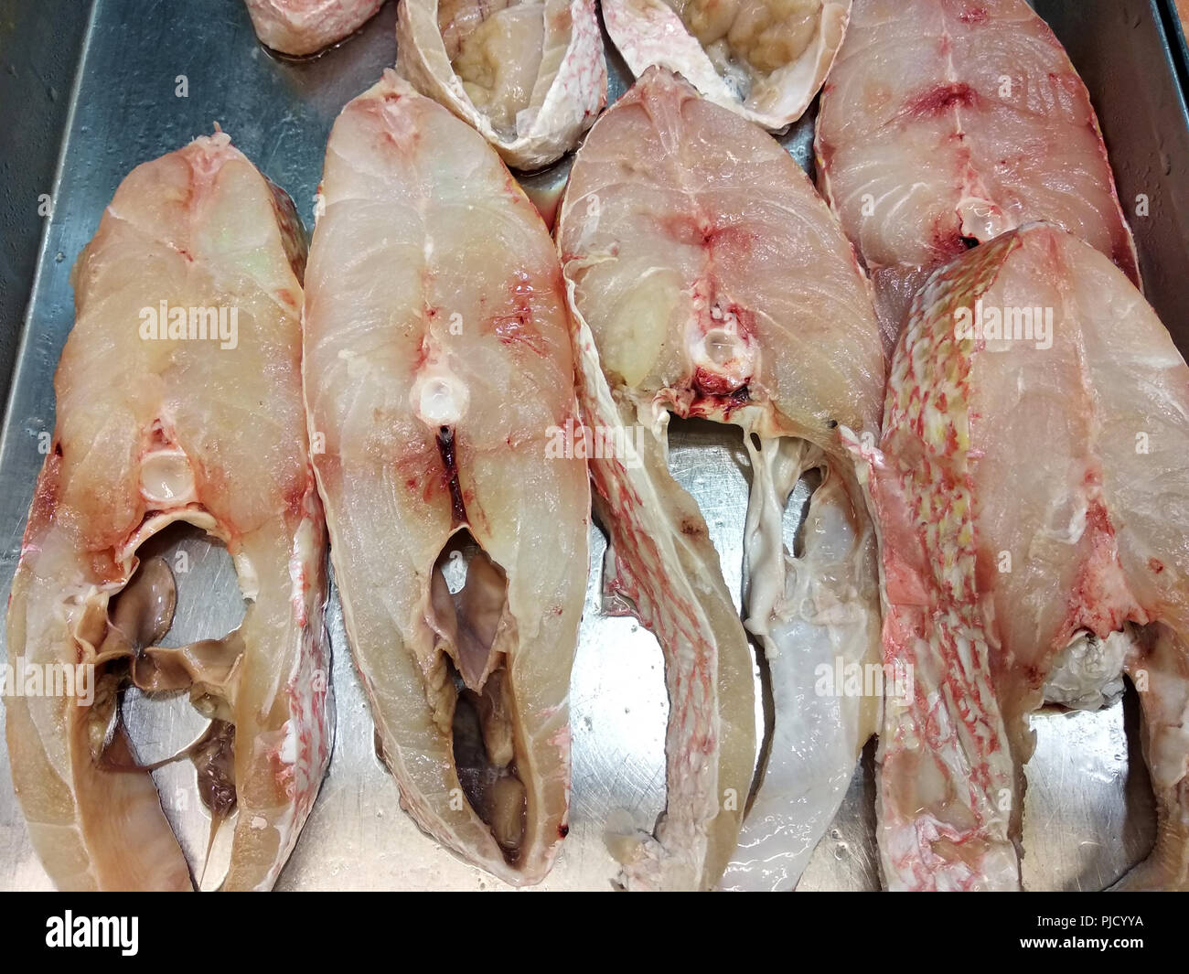 Carne di pesce che è stata tagliata e posta su un vassoio di acciaio inossidabile per la vendita. Foto Stock