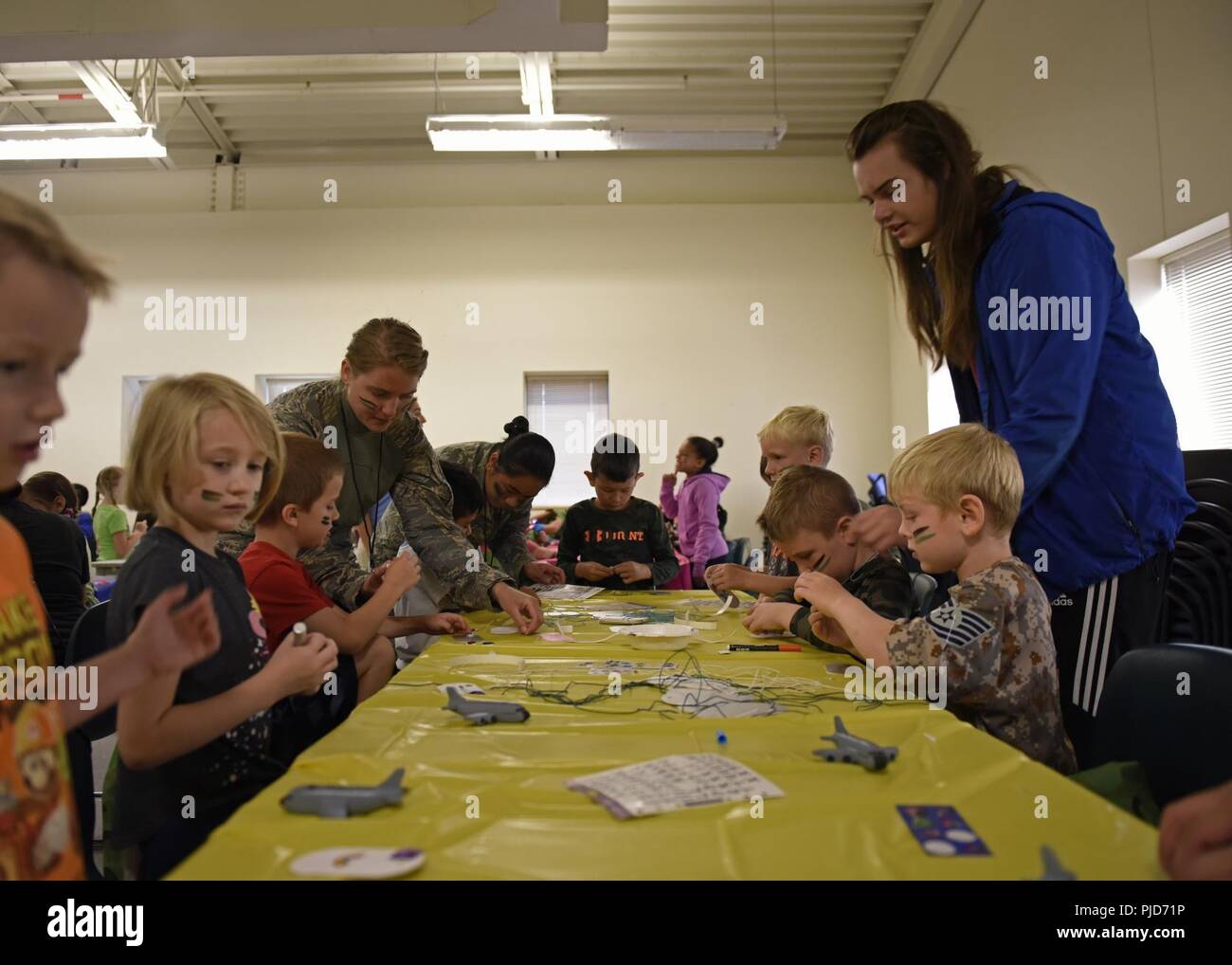 Fairchild aviatori militari di assistere i bambini fanno mock dog tag durante il funzionamento i bambini la comprensione delle operazioni di distribuzione a Fairchild Air Force Base, Washington, 20 luglio 2018. Fairchild's Airman & Family Readiness Center hosted funzionamento KUDOS, che presenta le implementazioni in un modo divertente per diminuire l'ansia da separazione bambini attraversare durante i loro genitori la distribuzione. Foto Stock