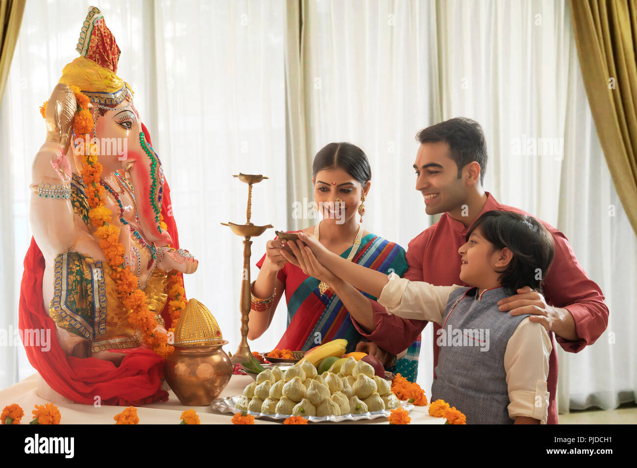 Famiglia nucleare illumina il diya per Ganpati Pooja su Ganesh chaturthi Foto Stock
