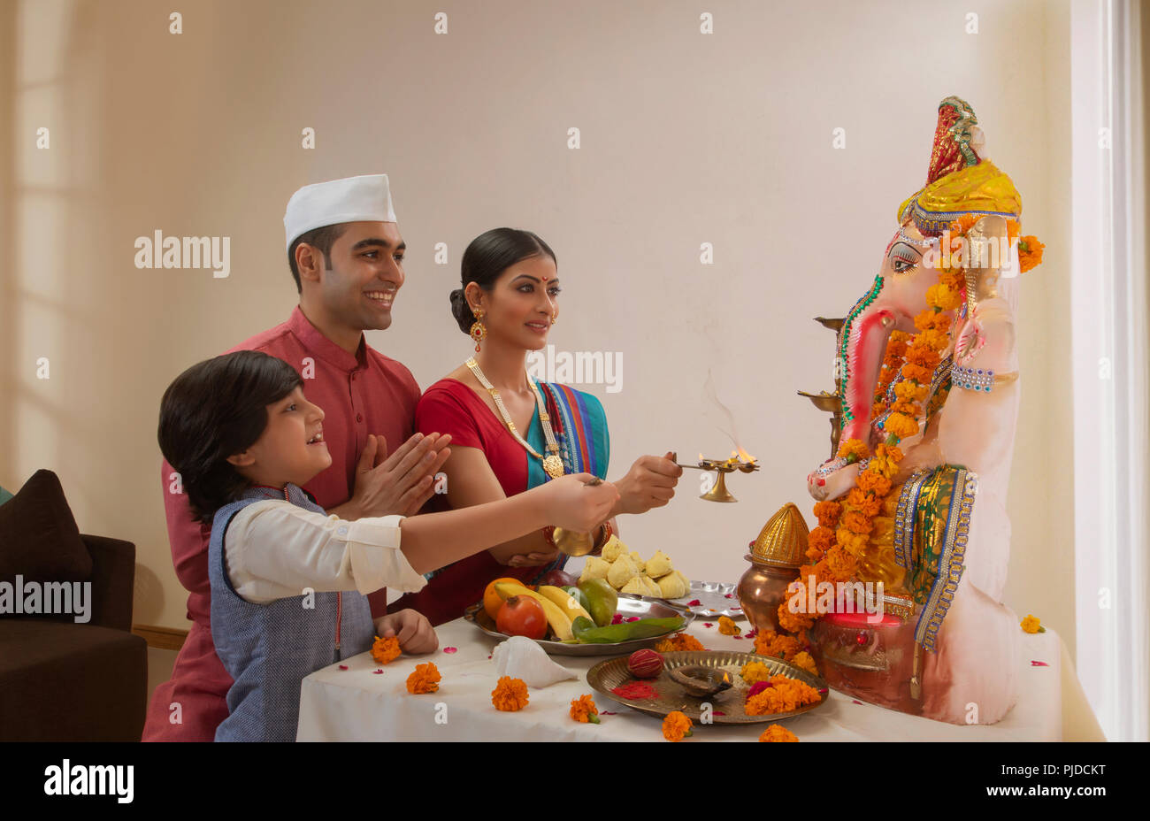 Famiglia di eseguire aarti sul Ganesh chaturthi in cui il bambino tiene il diya Foto Stock