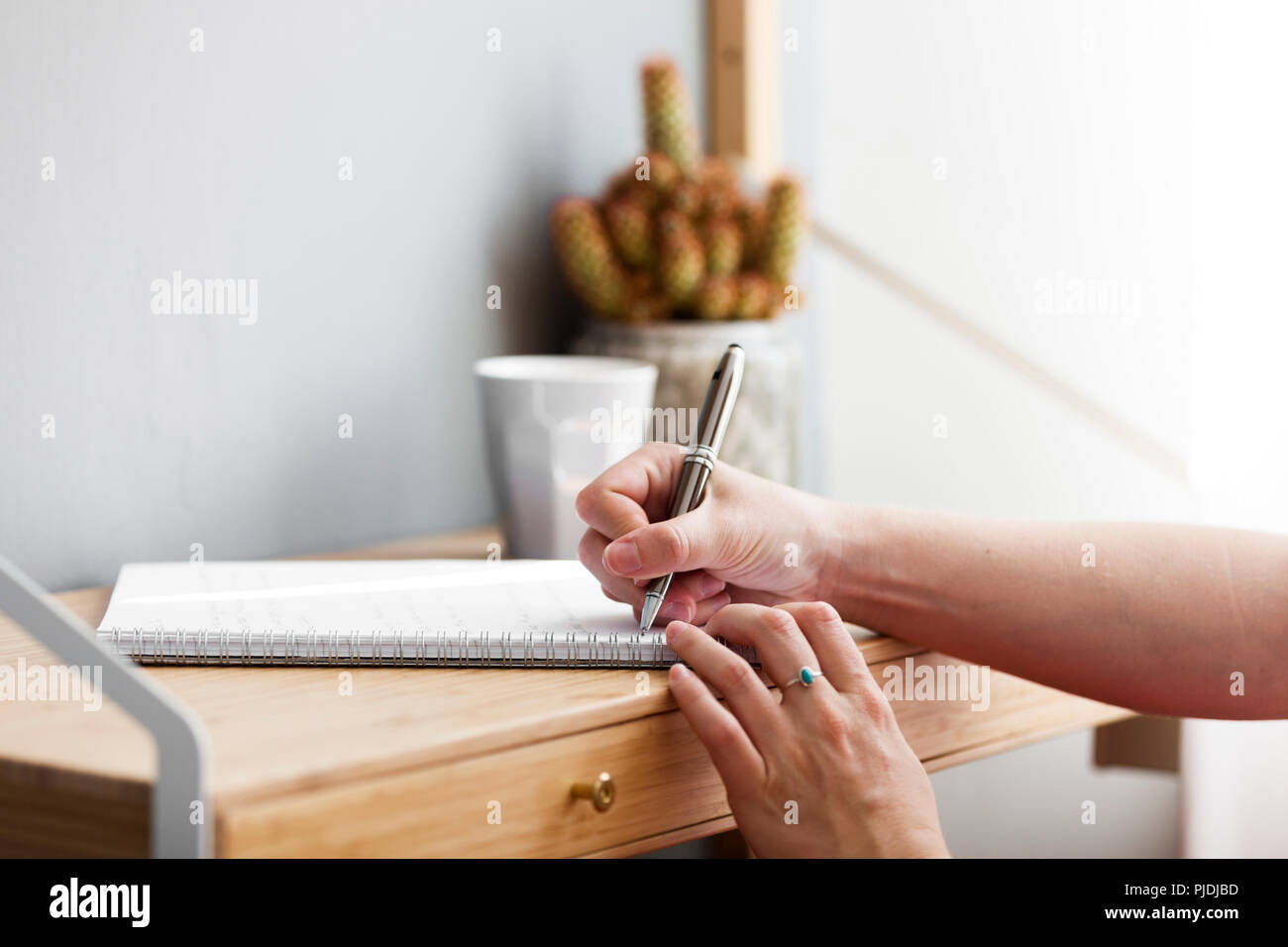 Scrittura di una nota sulla piccola casa scrivania con luce naturale di versare attraverso la finestra. Foto Stock