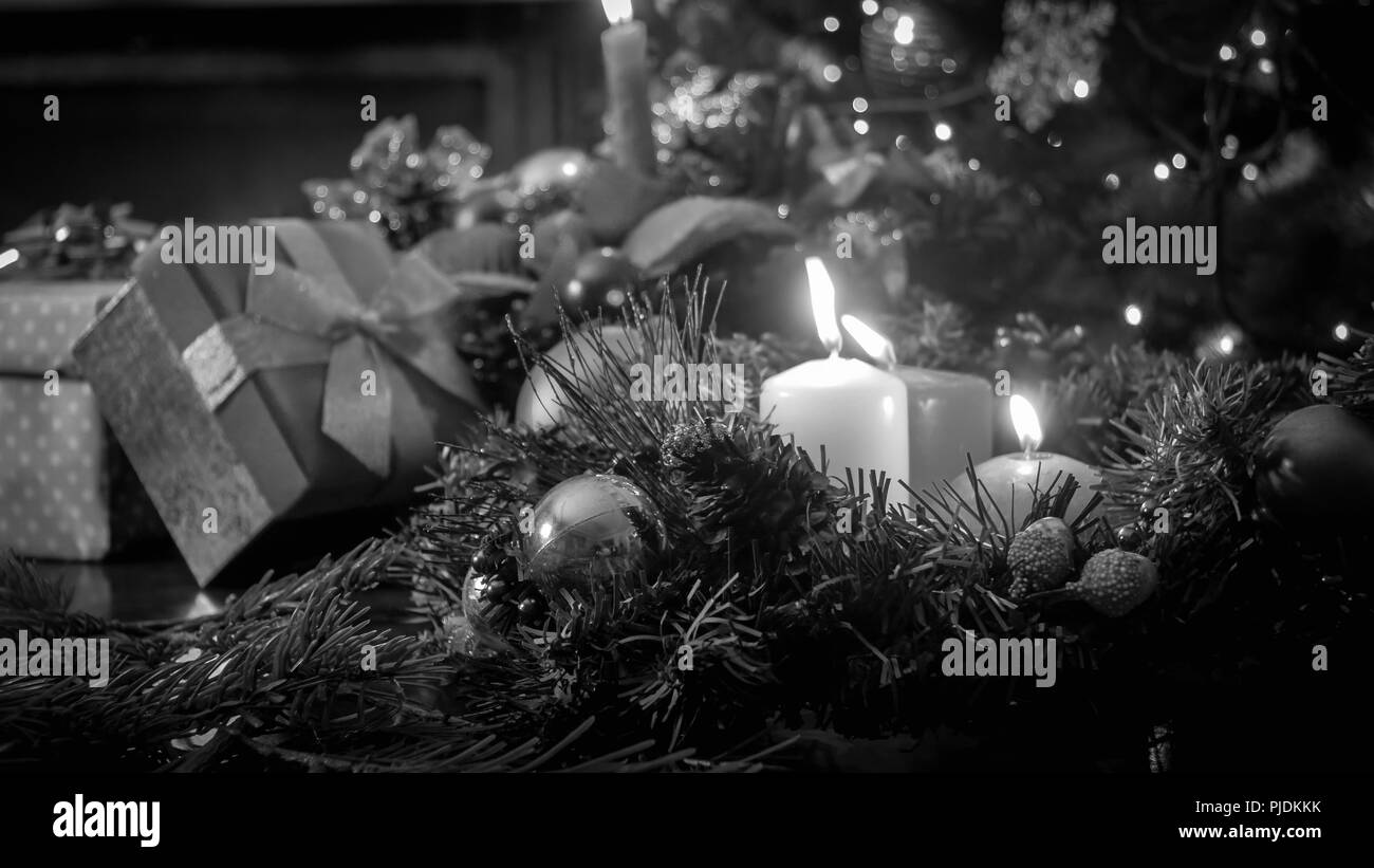 Immagine in bianco e nero di candele accese contro l albero di Natale e regali Foto Stock