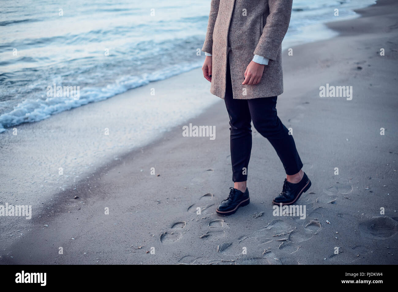 Giovane donna camminando sulla spiaggia, lasciando tracce nella sabbia bagnata, sezione bassa Foto Stock
