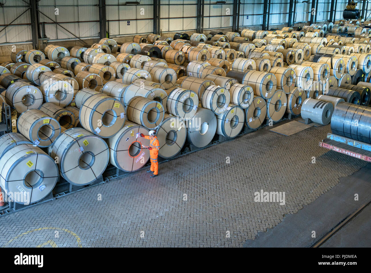 Lavoratore con le righe del foglio di acciaio in deposito a porto Foto Stock