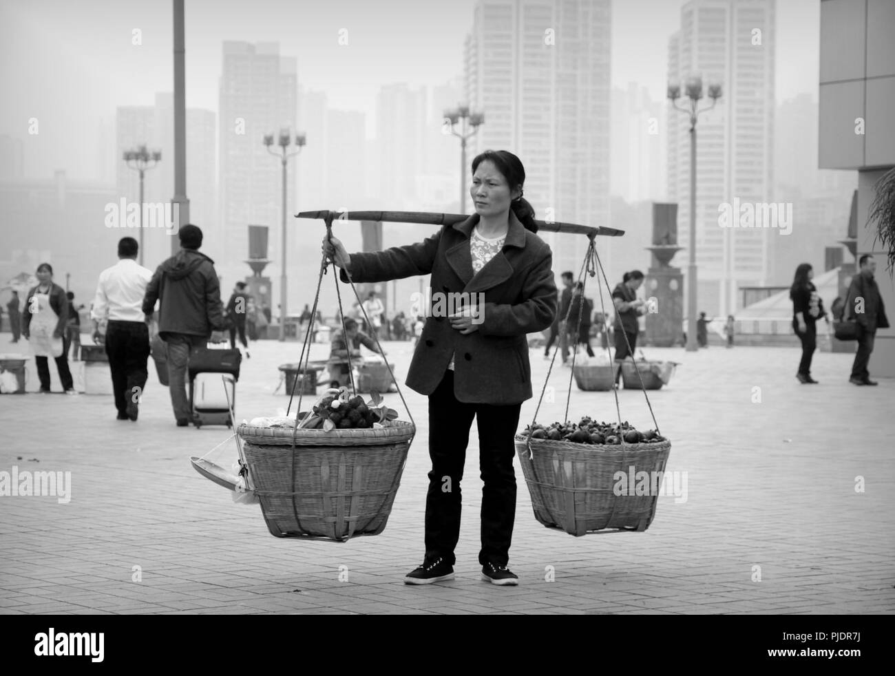 Una donna cinese che trasportano le verdure in vaschette a Chongqing. Foto Stock