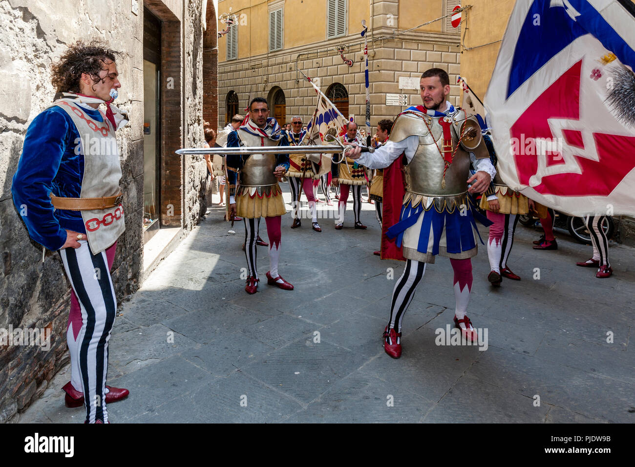 I membri del vincente Istrice (Porcupine) Contrada prendere parte in una rumorosa processione per le strade di Siena, il Palio di Siena, Siena, Italia Foto Stock