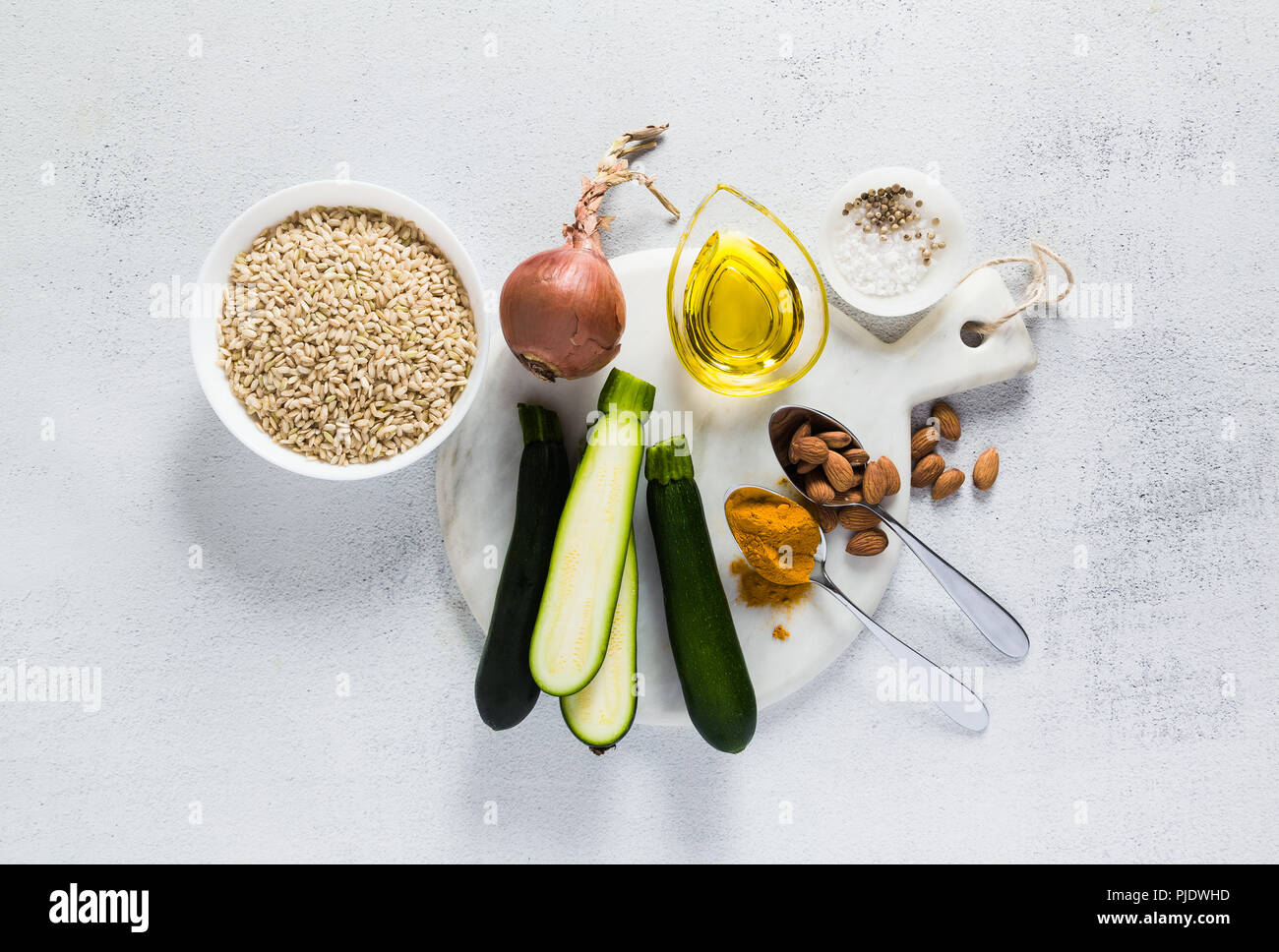 Ingredienti per il risotto con il riso integrale con zucchine e curcuma sul tavolo. Una sana italiana cucina vegana Foto Stock