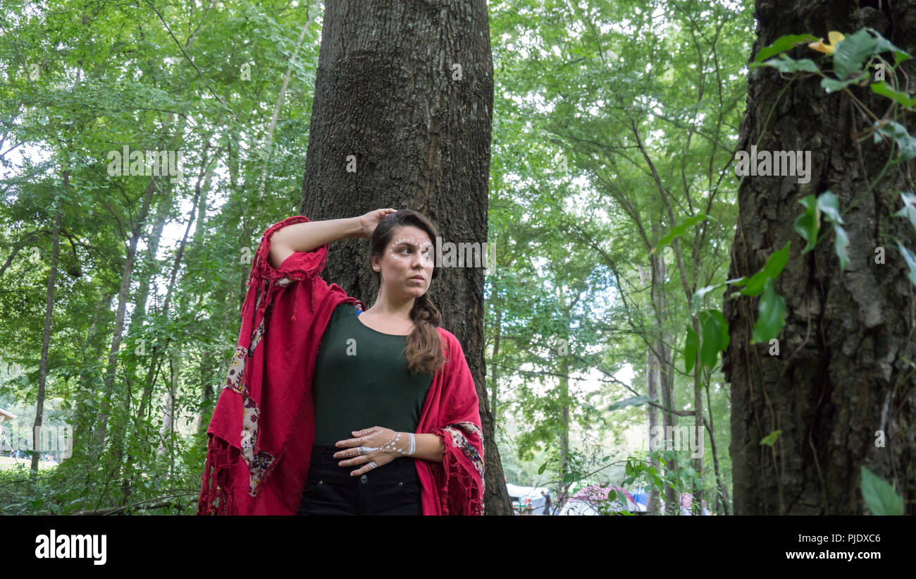 Giovani hippie bella bruna donna con lunga treccia capelli vicino ad un albero riflessivo e di pensiero Foto Stock