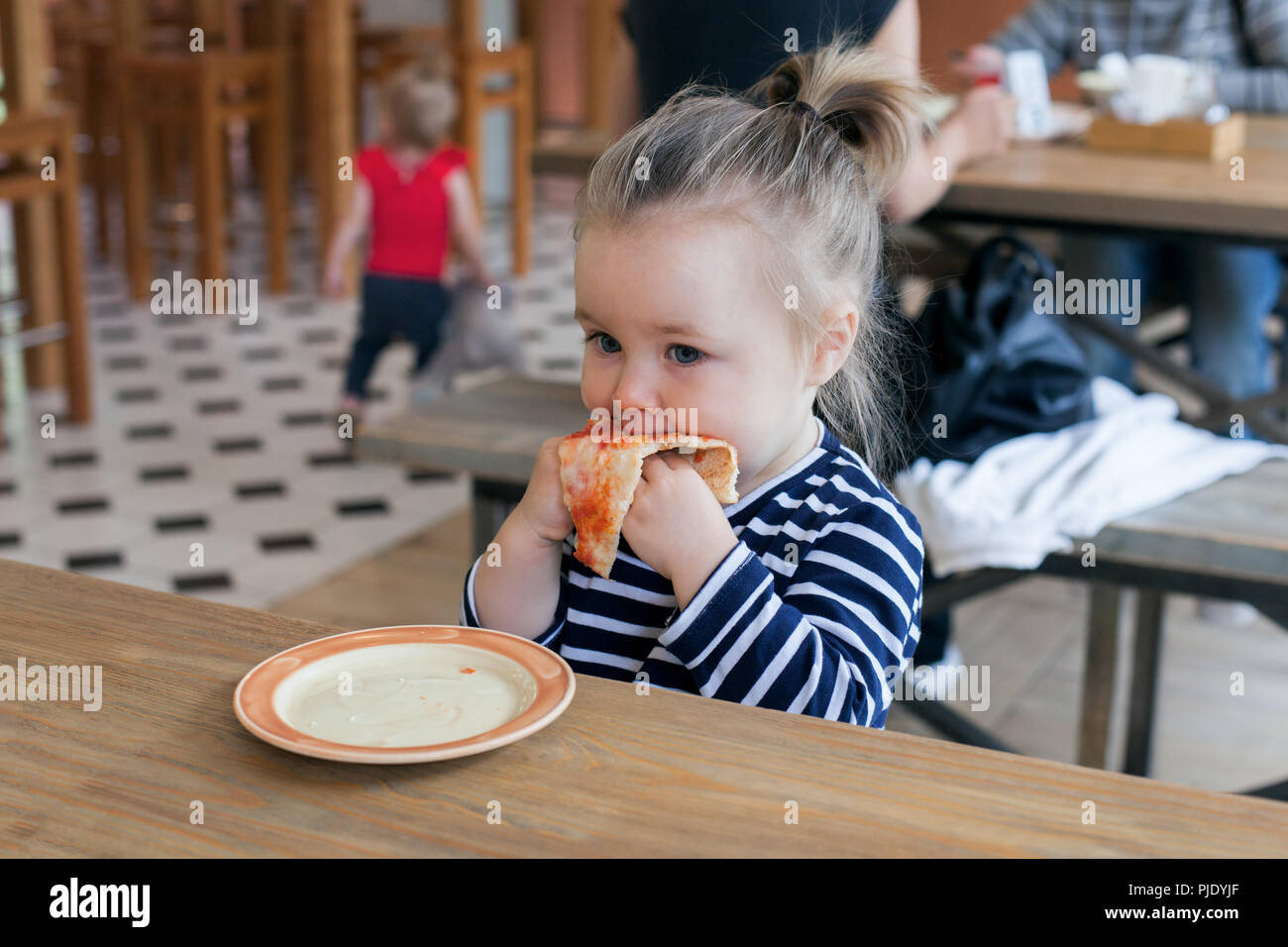 Carino piccolo 2 anni ragazza mangiare la pizza nel ristorante Foto Stock
