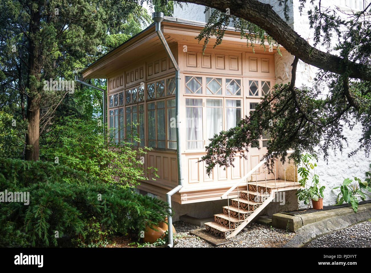 Ingresso alla casa dal giardino attraverso una veranda in legno con grandi finestre. Foto Stock