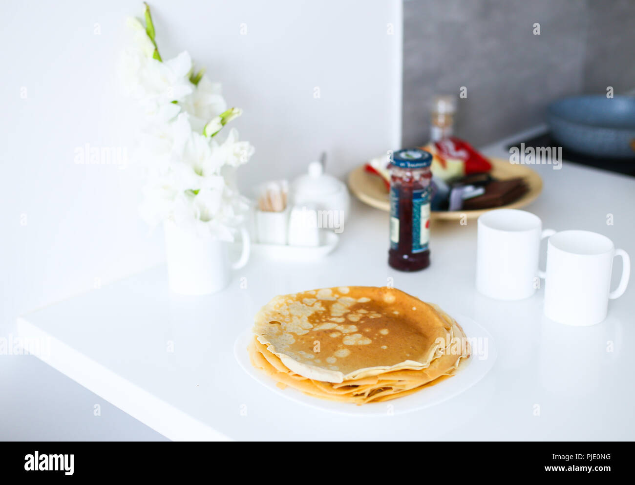 Gustose frittelle sulla piastra bianca nei pressi di fiori sulla cucina. Foto Stock