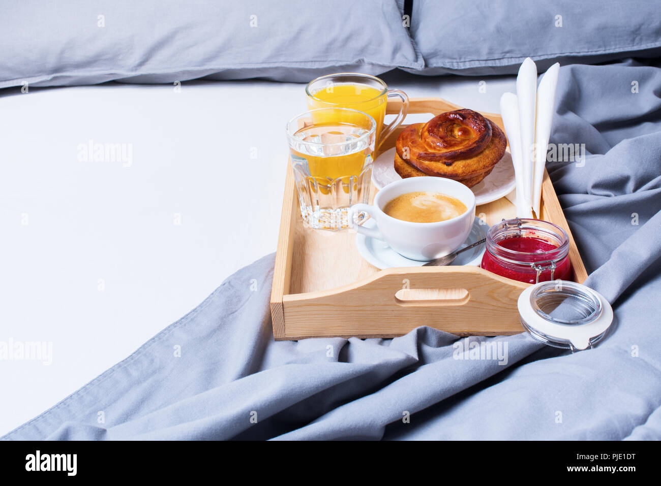 La prima colazione a letto Vassoio in legno Bun Caffè Grigio Biancheria da letto Biancheria cuscino Foglio Coverlet Hotel camera la mattina presto a sfondo Hotel concetto interno Foto Stock